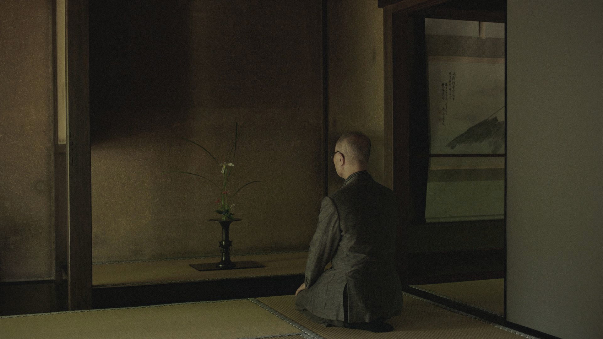 Un uomo in meditazione davanti a un ikebana in un interno tradizionale giapponese, scena tratta dal documentario Il Padiglione sull'acqua di Stefano Croci e Silvia Siberini.